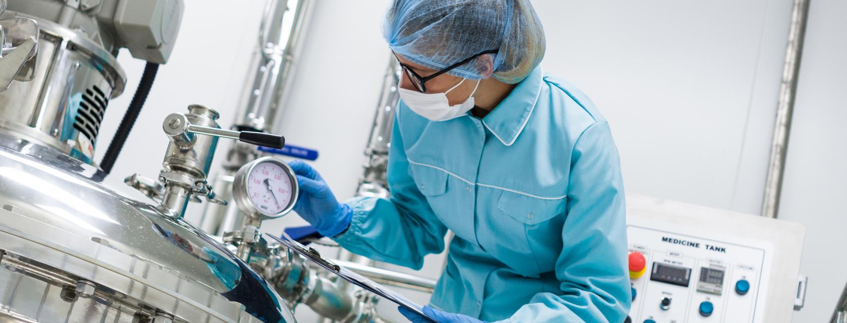 A lab technician using a clipboard and pen to check equipment settings